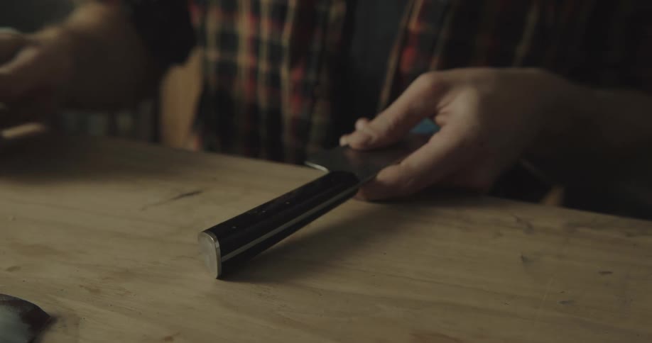 A person sanding a handle on a knife