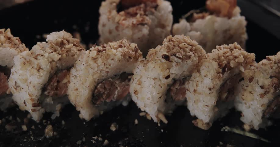 Pieces of sushi sit at an angle side by side on a black plate