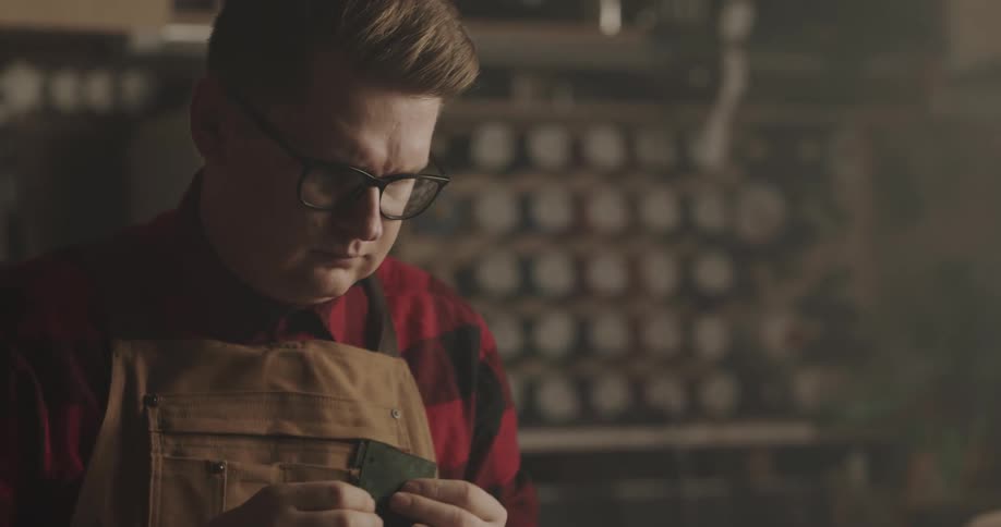 A man uses a tool to clean the edges of a piece of leather