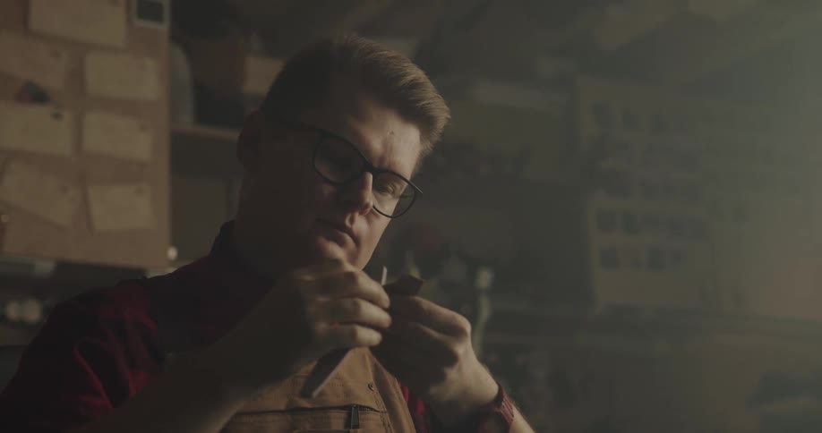 A shop owner carefully carves a piece of wood with a small blade