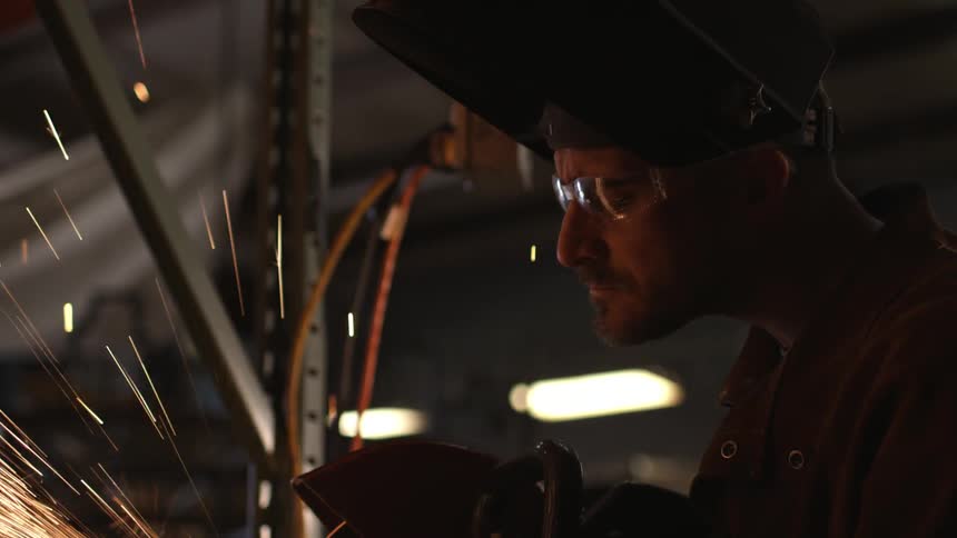 Sparks flying as a man uses a saw on metal