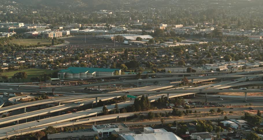 Cars travel on looping highways near commercial buildings and neighborhoods