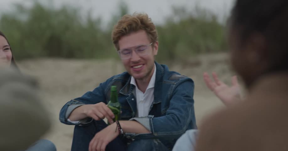 Group of friends sitting together in the nature while drinking beverages and chatting together