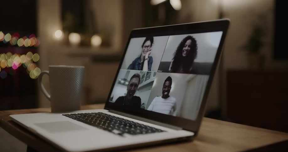 A laptop on a table next to a mug with a wall and a doorway in the background