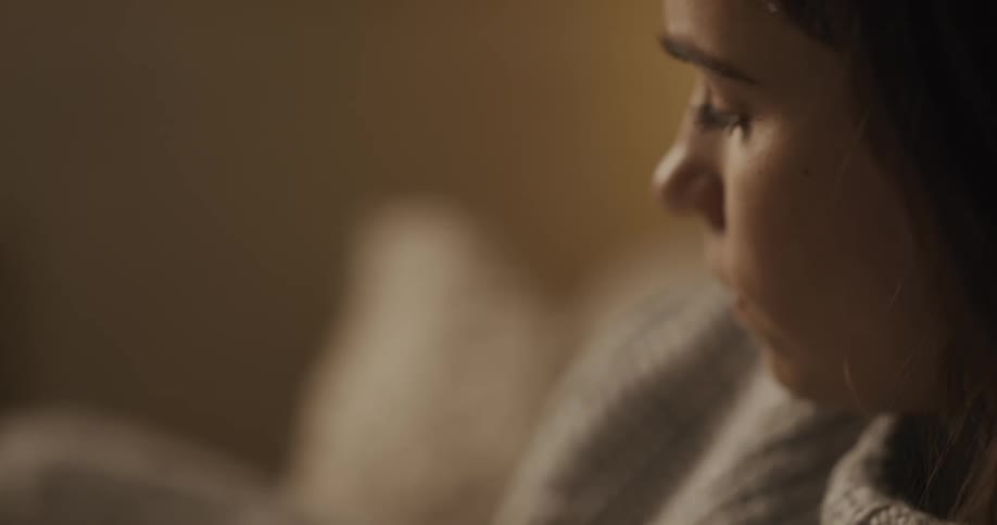 A woman in a room sitting on a couch wearing a sweater