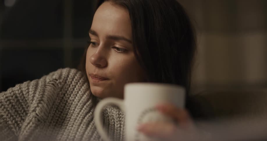 A woman sitting on a couch drinking from a mug