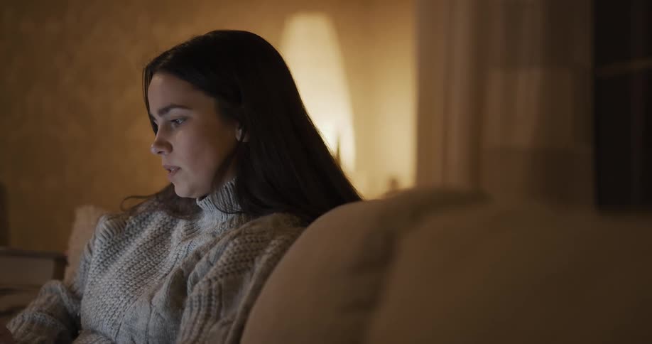 White teenager girl video calling while sitting at the couch alone
