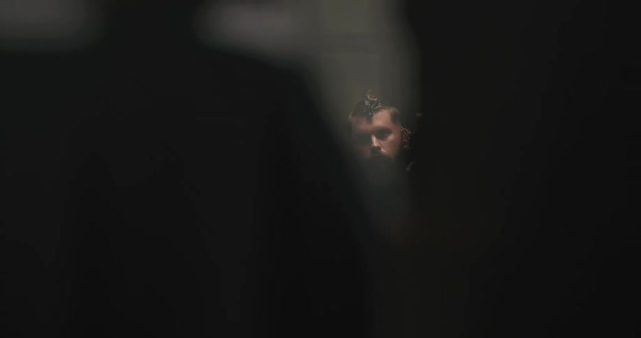A man in a barbershop getting a haircut with electric clippers with a mirror in the background