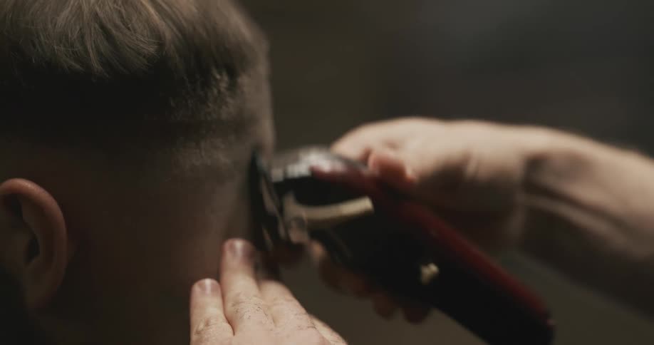 A man with electric clippers and a comb cutting another mans hair