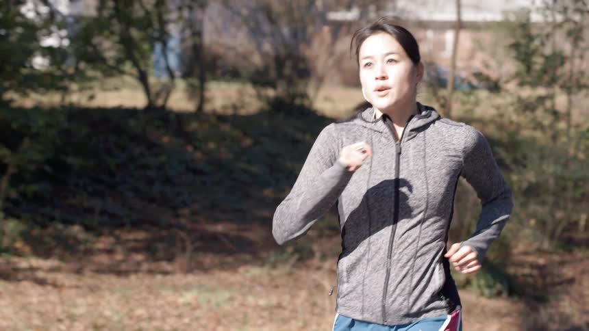 A woman is jogging outside on a sunny day