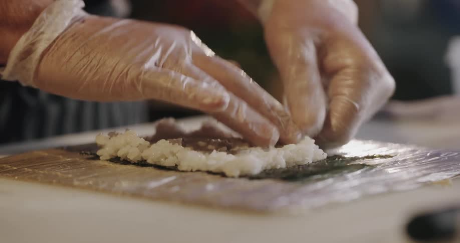 A person is making food indoors and wearing gloves