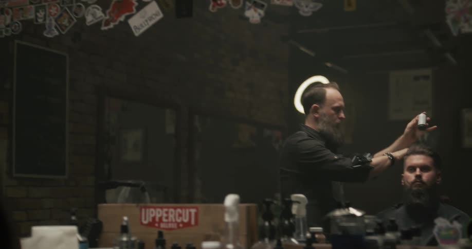 A barber sprinkles powder on a mans hair and rubs it in
