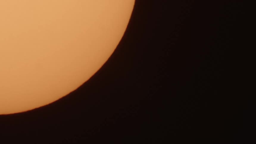 A yellow orange sphere moves across a black background