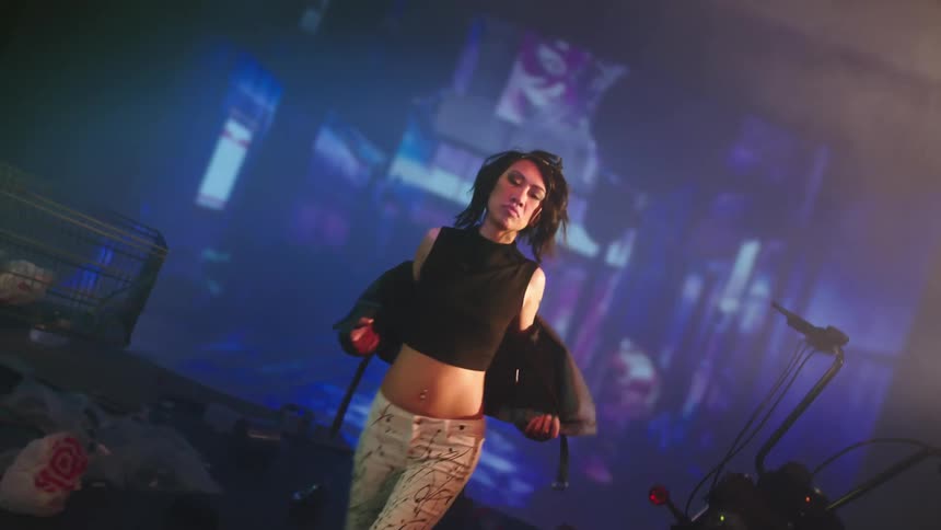 A woman with a jacket on a stage with a motorcycle and a shopping cart in the background