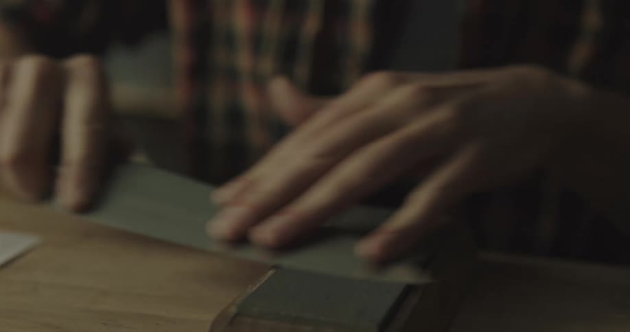 A person sitting at a desk sharpening a knife