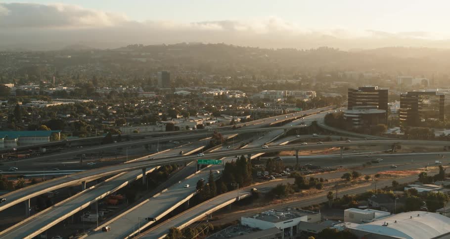Busy highway in a city with many buildings and mountains on the horizon on a cloudy day