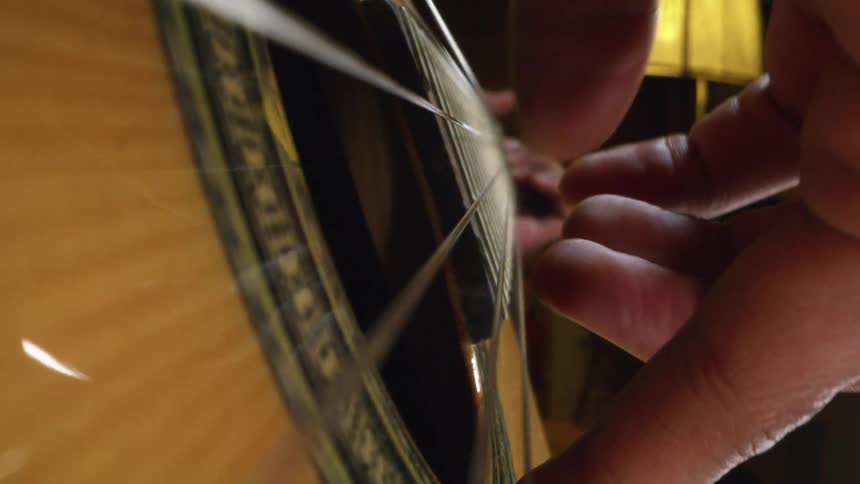 A person strumming an acoustic guitar with their fingers