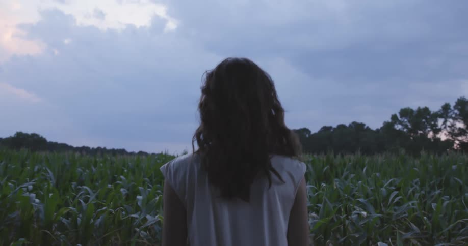 A woman stands in the tall green grass