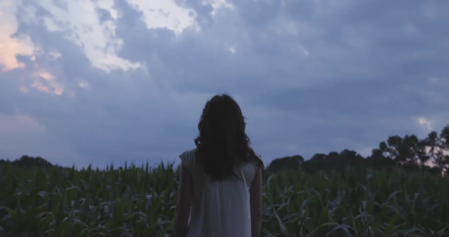 A woman stands in a field of corn