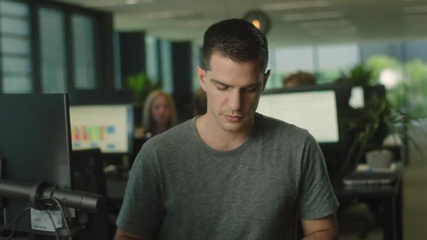 Man sits at an office desk and turns his head to his right then his left