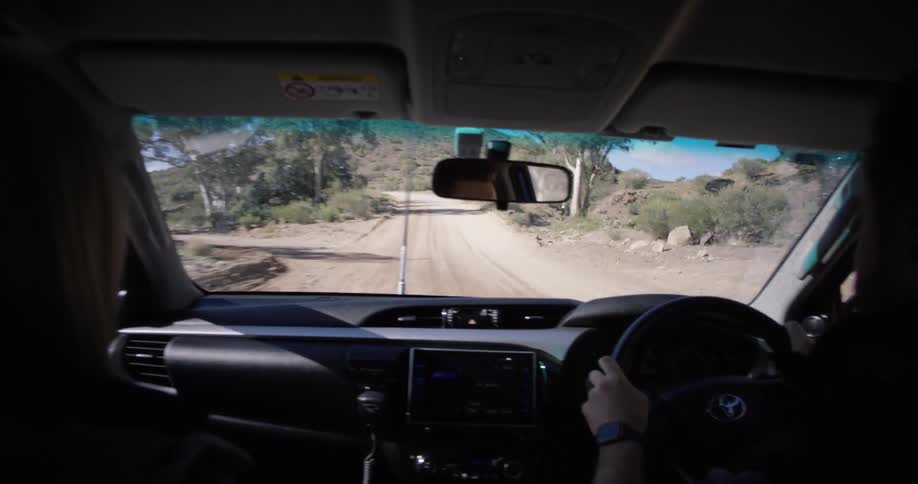 Man drives car uphill on dirt road