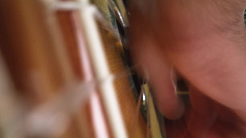 Person playing an acoustic guitar and strumming the strings with their hand