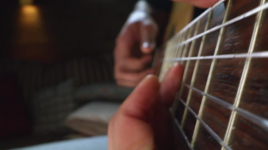 Fingers playing a guitar in a dark room