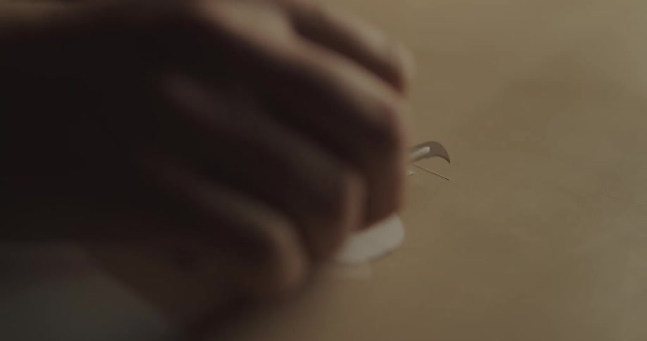 A woman cuts paper with a small blade as she crafts