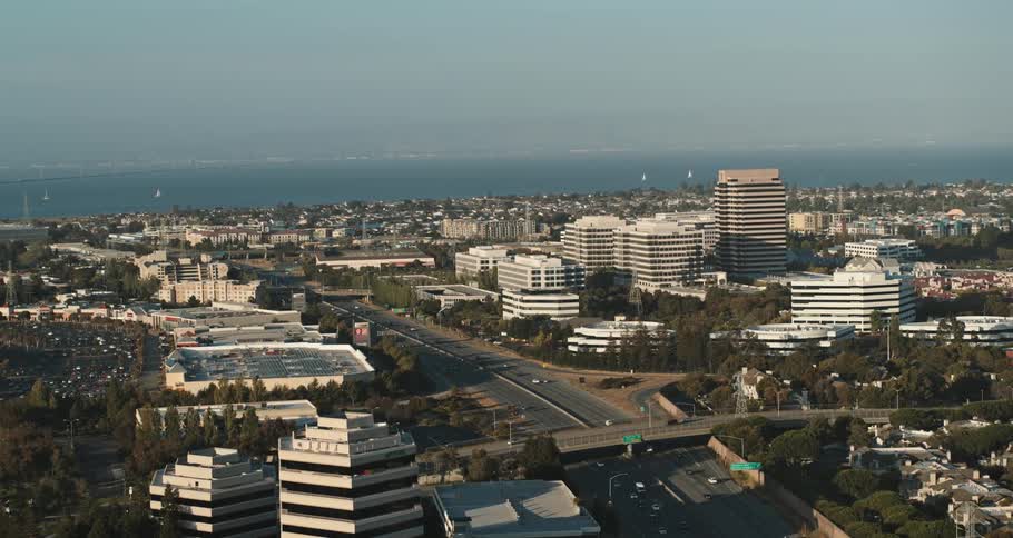 Traffic flows down freeway crossing through city toward foggy ocean