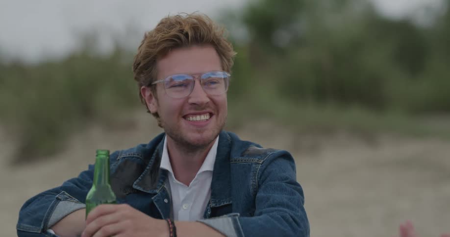Male laughing hanging out drinking beer outdoors with friends