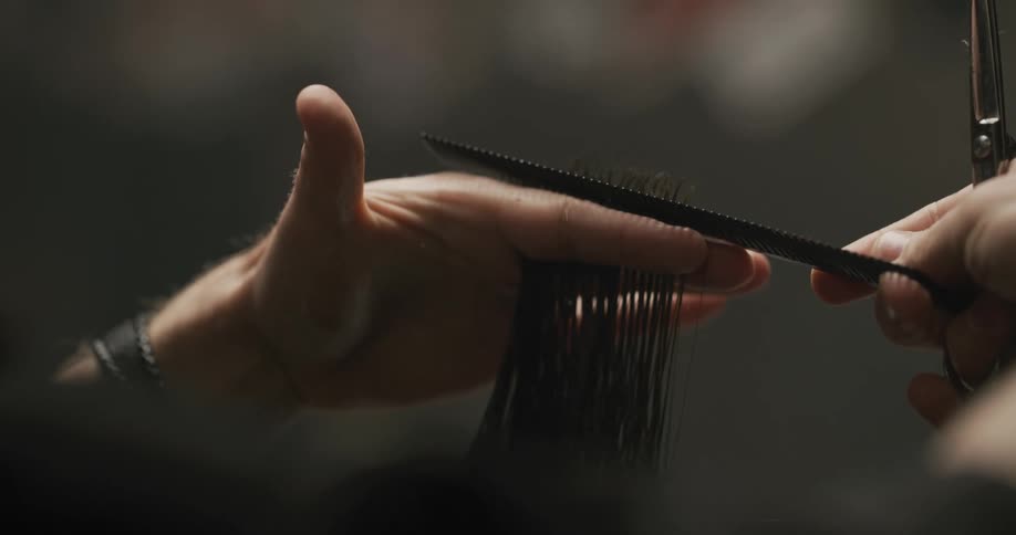 Hair dresser uses scissors and a comb while cutting a clients hair