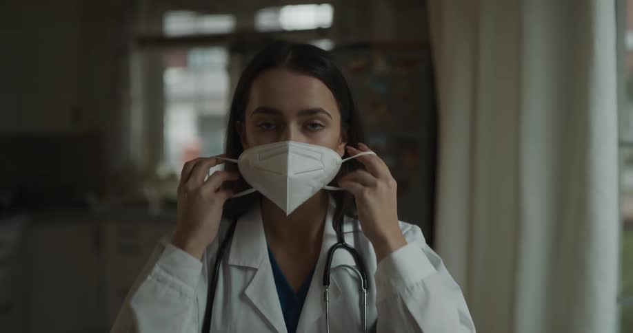 A doctor poses in hospital and puts on a white face mask