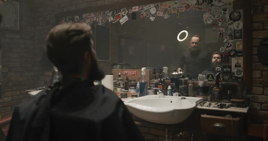 A man sitting on a chair in a barbershop with a wall and a mirror in the background