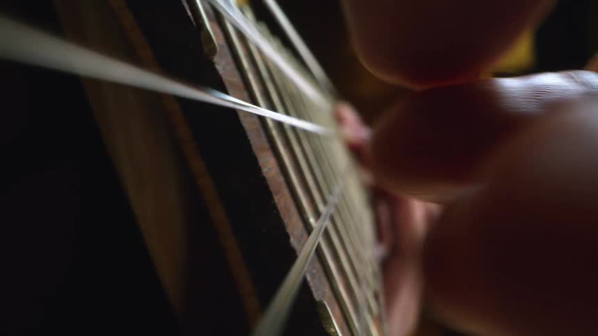A person in a room playing a guitar with a lamp in the background