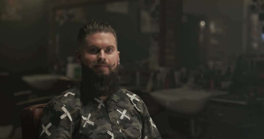 Man sitting in shadowy room strokes beard