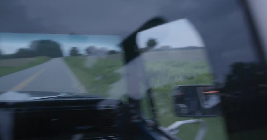 A man driving a vehicle on a road with trees the sky and clouds in the background