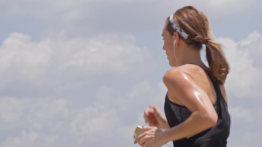 A sweaty woman jogs outside in the city