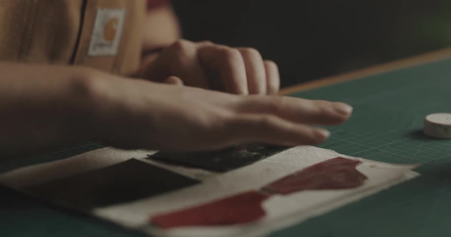 A person in a workshop next to a table spreading a substance on leather
