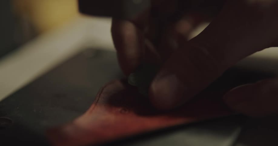 A person stamping a logo on leather