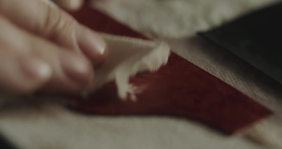 A person in a room wiping leather with a cloth