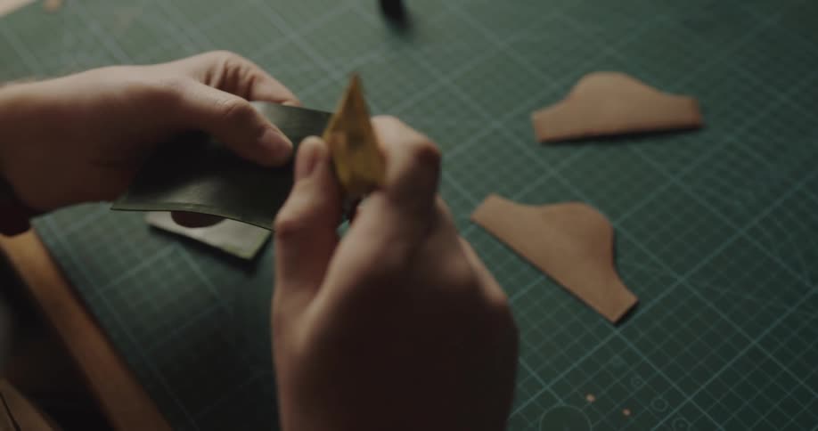 A person gluing handcrafted pieces of leather over a workbench