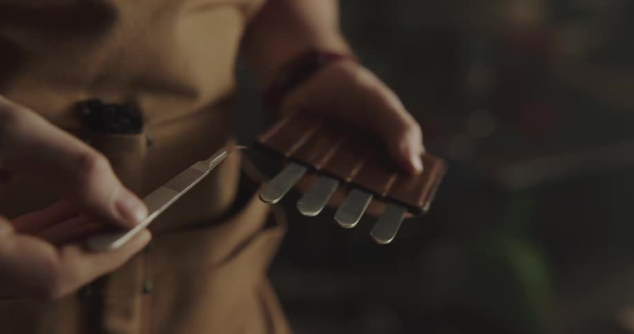A person in a workshop removing a tool from a leather sleeve