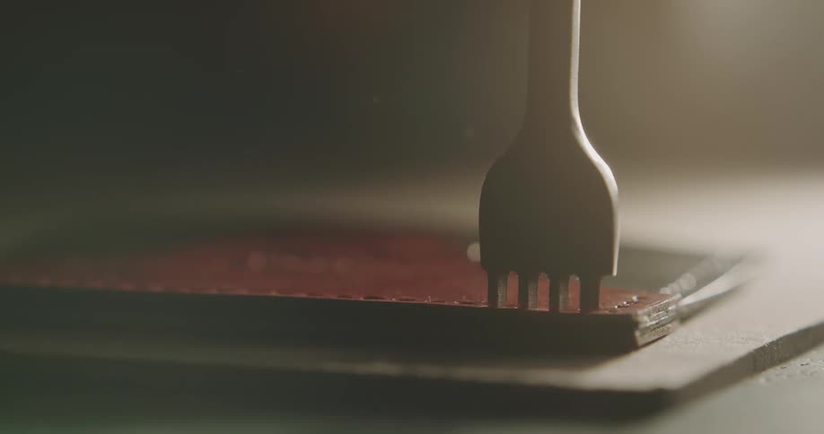 A person in a room using a tool to puncture leather on a table