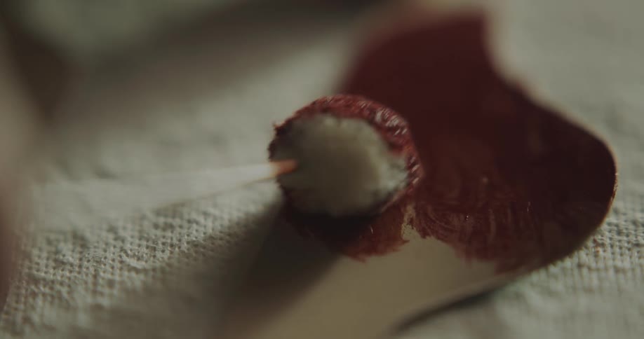 A person in a room adding red dye onto leather