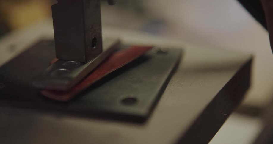 A man stamps a logo on the back of a leather product