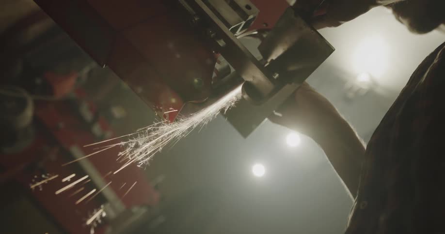 A person in a workshop using a tool with sparks