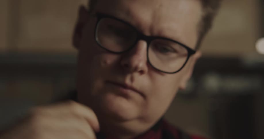 A man in a room with glasses looking downward