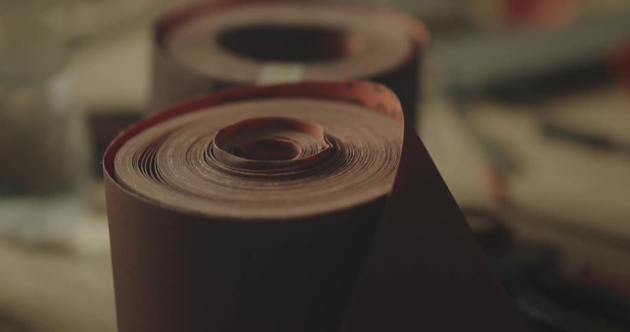 Rolls of sanding paper resting over a workbench in a workshop