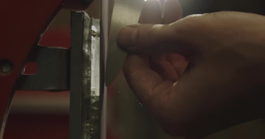 A man sharpens a small knife on a sanding machine