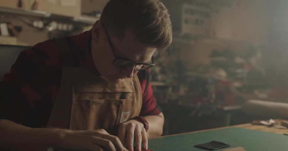 A man sitting at a table crafting with leather